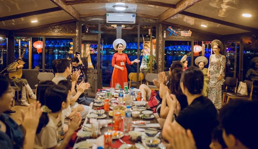 Đoàn thuyền biểu diễn nghệ thuật trên sông Hương với phông nền cầu và sân khấu đèn rực rỡ.