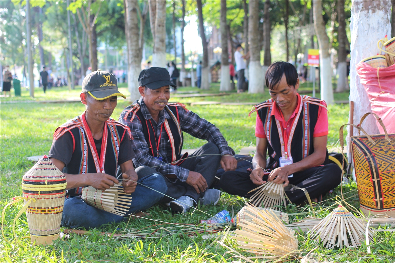 Ba nghệ nhân ngồi ngoài trời, tập trung đan lát tre nứa truyền thống.