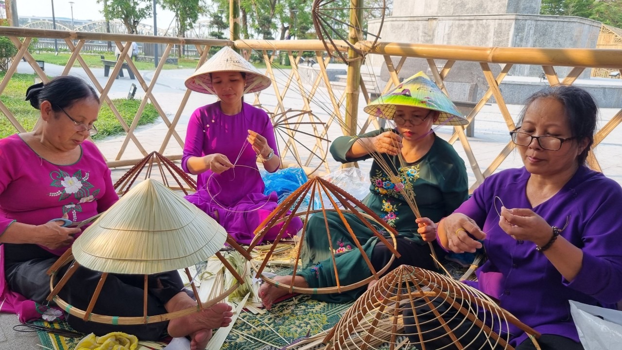 Bốn người thợ làm nón lá đang ngồi chằm nón ở làng nghề Tây Hồ, Huế.