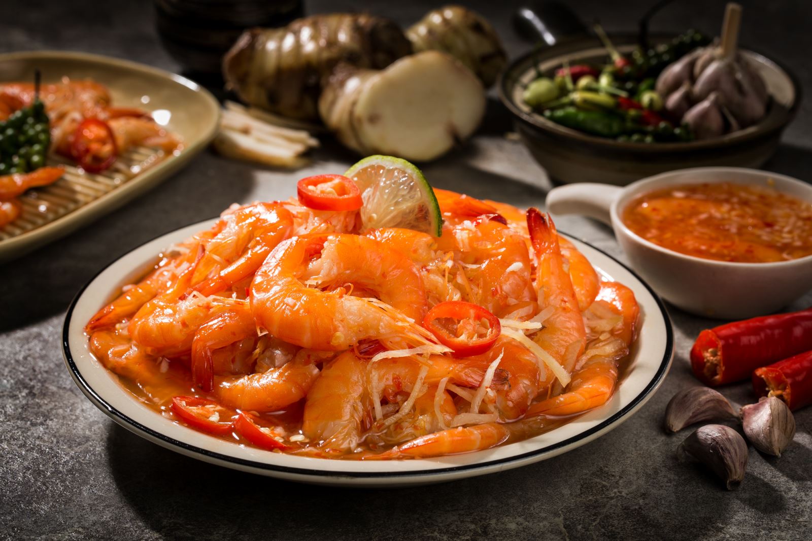 Đĩa mắm tôm chua với những con tôm màu hồng cam, trang trí với ớt, tỏi, và chanh thái lát.
