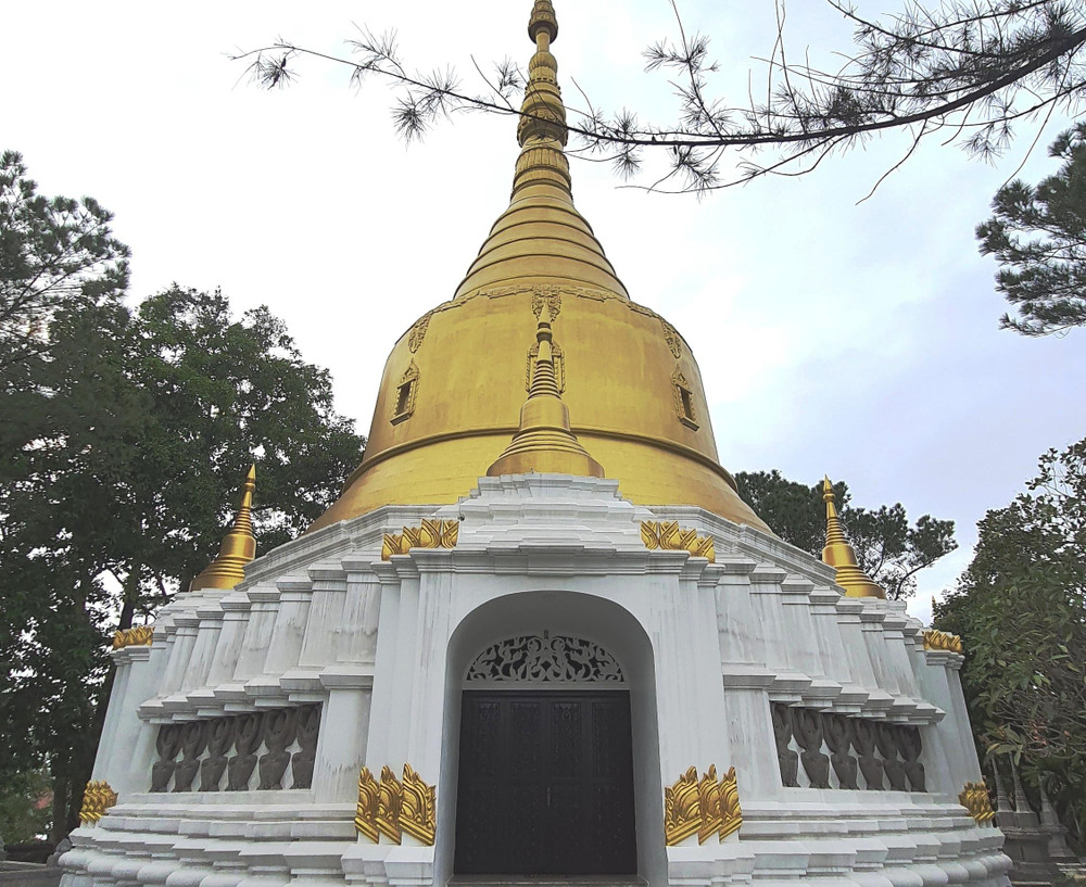 Một ngôi tháp nhỏ màu trắng với bức tượng Phật ngồi ở Chùa Thiền Lâm Huế.